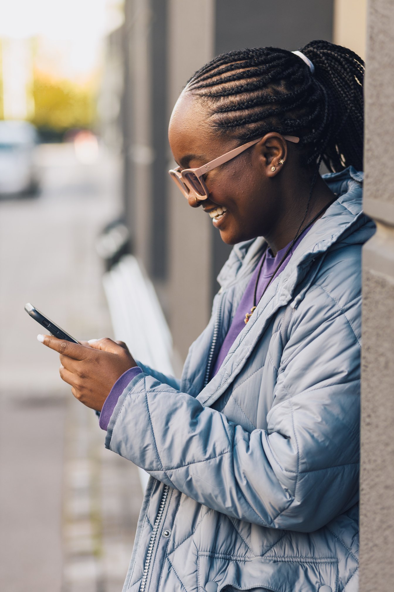 Happy and smiling young black woman texting on her phone